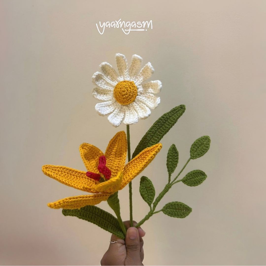 Hand holding a crocheted flower with a plain background